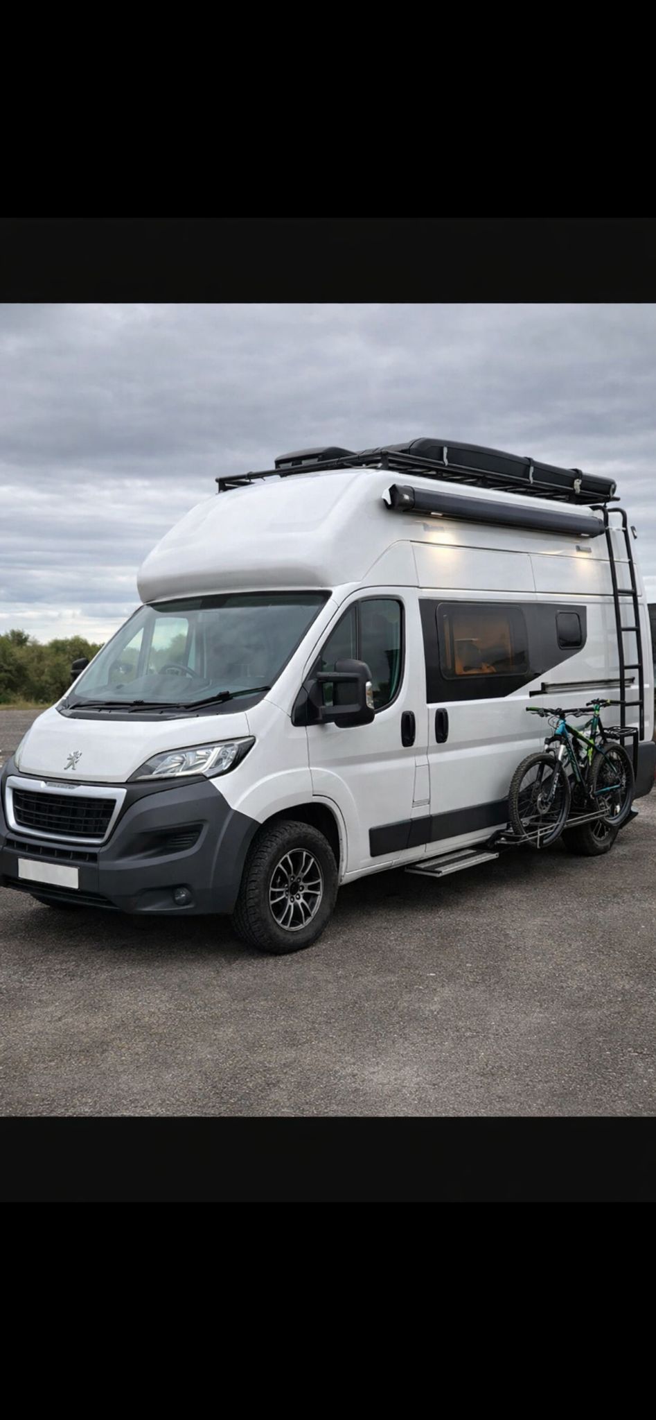 White campervan with roof extension and bike rack